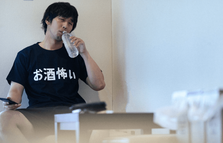 二日酔いで水を飲む男性